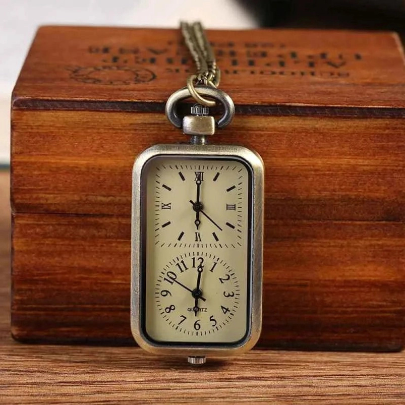 Rectangular dual-dial steampunk pocket watch with antique bronze frame and off-white dials displayed on wooden desktop