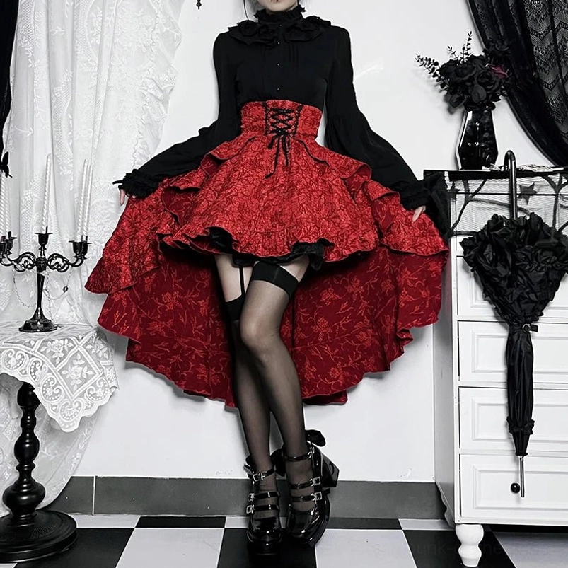 Red steampunk high-low skirt with layered ruffles and corset-style waistband on model, front low-angle view showcasing jacquard fabric texture and dramatic hem