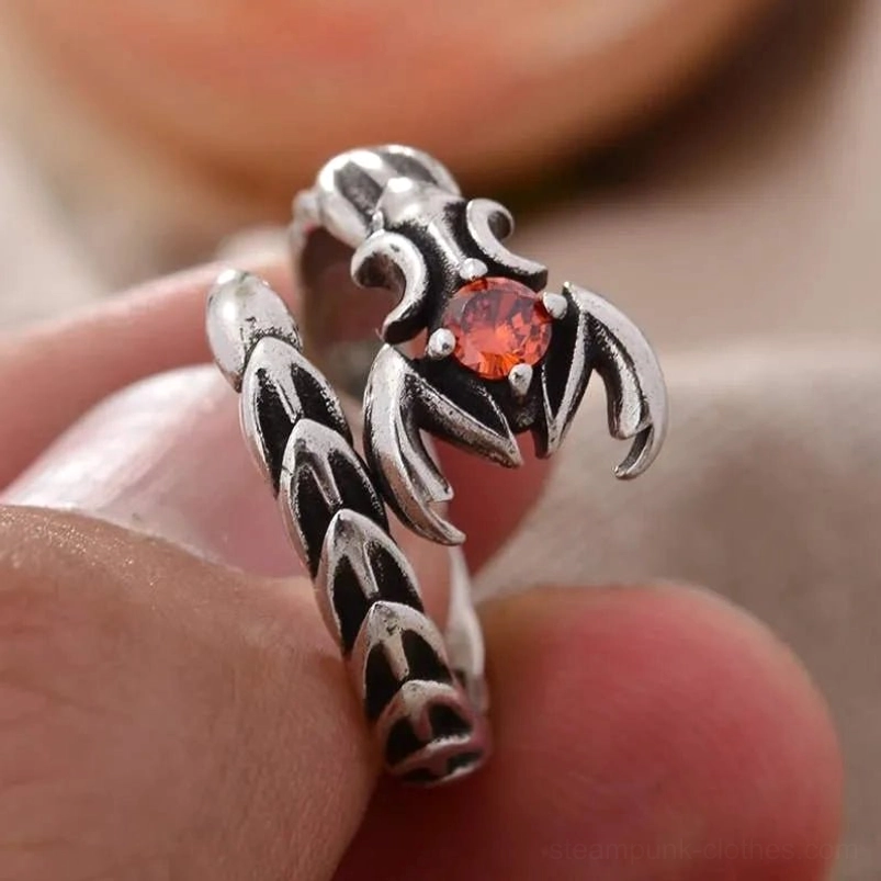 Scorpio steampunk ring with darkened silver finish and scale-patterned shank worn on male finger - close-up side view against light background