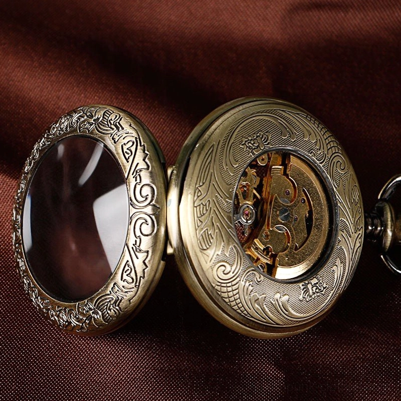 Steampunk pocket watch side view with transparent display window showing carved floral patterns and exposed mechanical movement