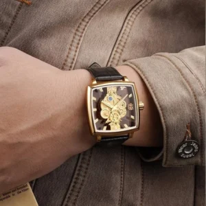 Square steampunk watch with gold case and brown leather band worn on male wrist, showcasing daily casual wear styling with brown jacket
