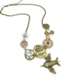 Steampunk airplane necklace with bronze aircraft pendant and intricate gear charms in mixed metal tones, left side flat lay view