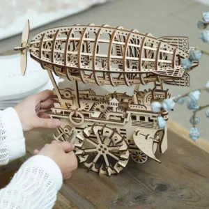 Steampunk wooden airship 3D puzzle model with laser-cut gears and mechanical framework displayed on wooden table with decorative botanicals