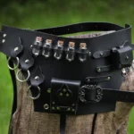 Steampunk alchemist potion waist belt featuring black matte PU leather, five corked glass vials, ornate antique metal buckles, D-rings, and decorative studs - front three-quarter close-up view on wooden stump with grass background