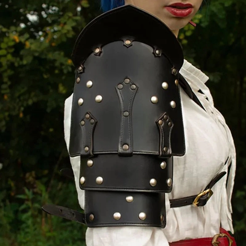 Close-up front detail of steampunk leather shoulder pauldron featuring multi-layered black vegan leather, decorative hand-stitching, and brass metal fasteners with industrial rivet placement