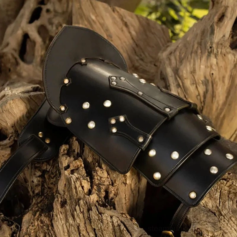 Flat lay close-up of steampunk leather shoulder pauldron showing multi-layered plate structure, hand-placed silver round rivets, adjustable leather fixing strap on weathered wooden surface