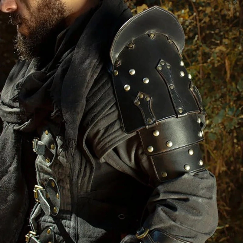 Bearded male model wearing black leather steampunk shoulder armor with silver rivets, left side angle view, paired with medieval-style outfit in grassland outdoor setting