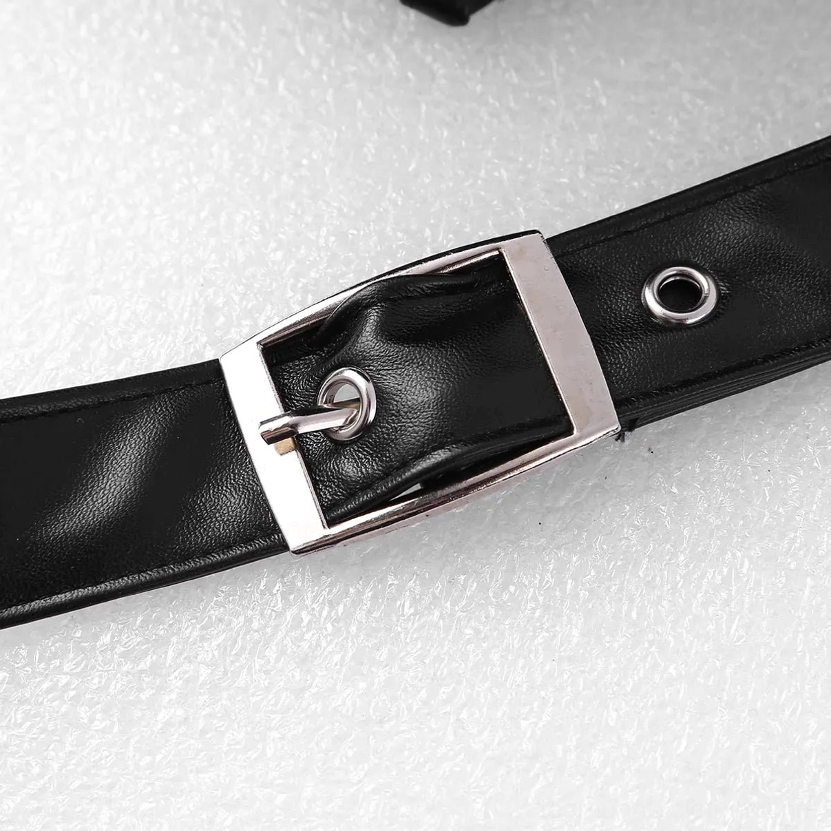 Fastening strap detail of steampunk armor featuring black faux leather material, silver square buckle, and adjustment eyelet for precise customizable fit