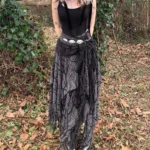 Steampunk asymmetrical midi skirt with bare branch print worn by model in outdoor woodland setting, showcasing layered lace sash and irregular hem