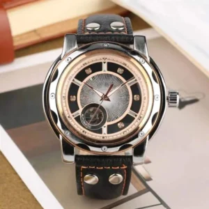 Steampunk mechanical watch frontal view showcasing stainless steel case and orange contrast stitching on calf leather strap, displayed on vintage book and magazine