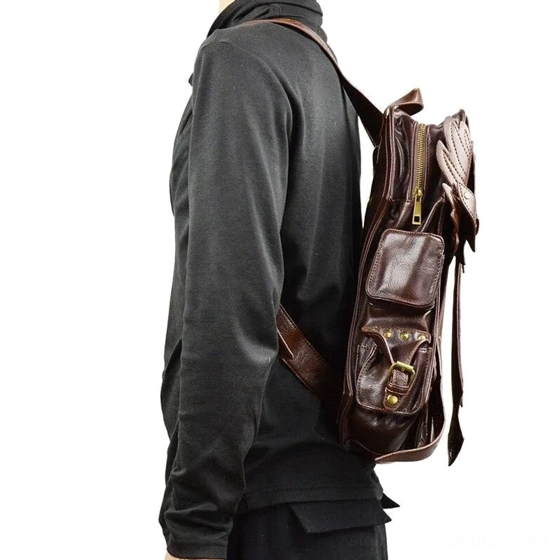Steampunk leather backpack side profile worn by male model in dark long-sleeve top, showing brass buckle compartment, zippered pockets, and adjustable shoulder strap