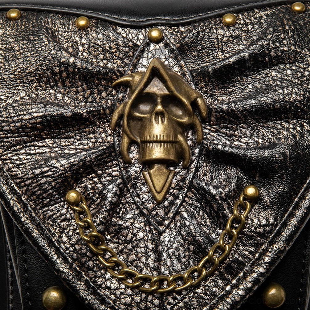 Extreme close-up macro detail of steampunk bag front showing crackled metallic leather texture, bronze grim reaper skull emblem and gold chain accents