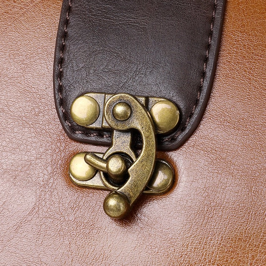 Macro close-up of antique brass twist lock clasp mechanism on steampunk bag showing vintage toggle lock detail and surrounding leather texture and finish
