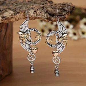 Steampunk bee drop earrings with dual-tone silver and gold metals, featuring intricate gear and heart charms on wooden table with floral background