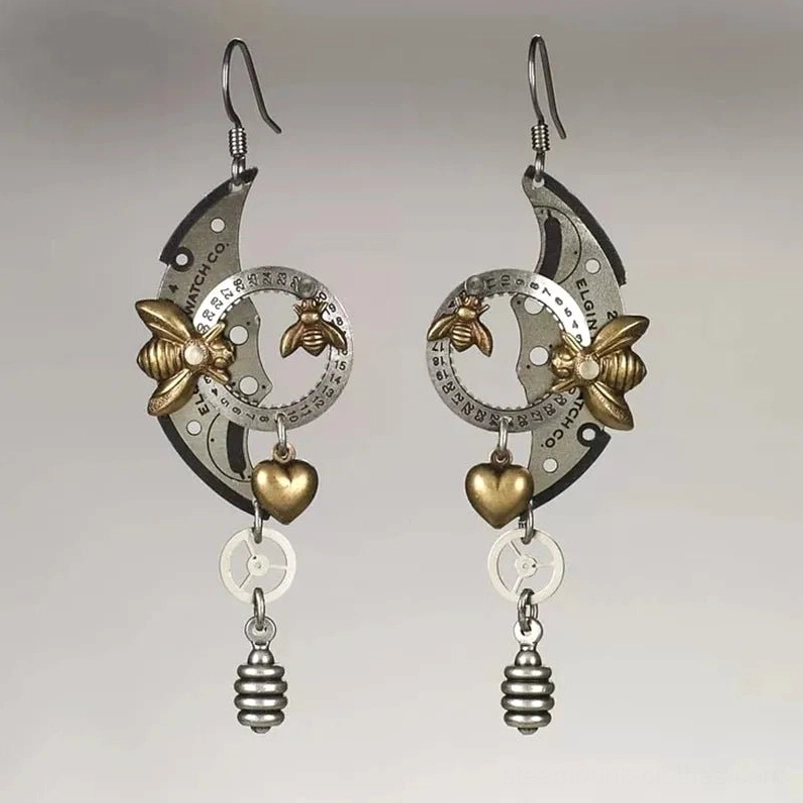 Steampunk bee earrings with engraved moon accents and mixed-metal dual-tone design on neutral gray studio background