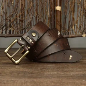 Steampunk corset belt detail showcasing intricate hand-stitched cross-stitch work, engraved geometric patterns, antique brass hardware with warm patina, overhead angle on natural wooden backdrop—demonstrating precision Victorian-era inspired craftsmanship