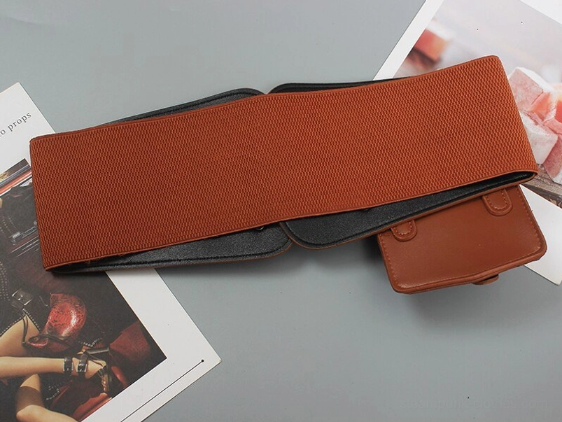 Flat lay overhead view of folded brown steampunk waist belt featuring elastic waistband foundation and detachable pouch compartment with buckled flap on magazine surface
