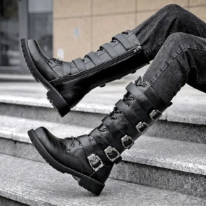 Steampunk mid-calf biker boots worn by model in dark wash jeans, side low-angle view showing side zipper and metal buckle decorations on stone staircases