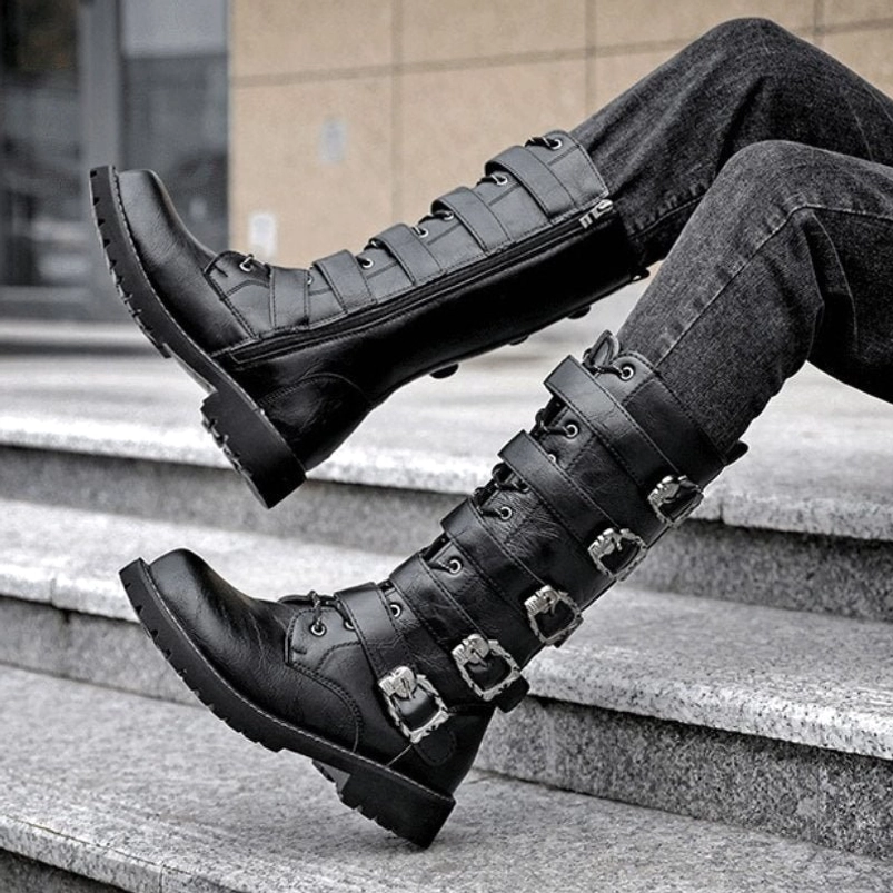 Steampunk mid-calf biker boots worn by model in dark wash jeans, side low-angle view showing side zipper and metal buckle decorations on stone staircases