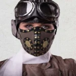 Male model wearing steampunk biker mask with flying goggles helmet, front half-body view showcasing brown faux leather construction and bronze metal rivets