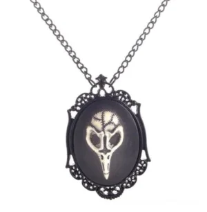 Close-up of steampunk bird skull pendant necklace featuring intricate black floral filigree frame and engraved avian skeleton motif on dark oval base with curb chain