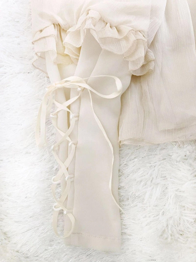 Close-up detail of steampunk blouse lace-up bow cuff with ruffled edge and crinkled cream white chiffon fabric texture