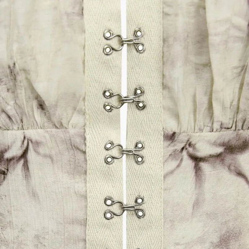 Metal hook-and-eye closure detail of steampunk crop top, silver fasteners on linen fabric