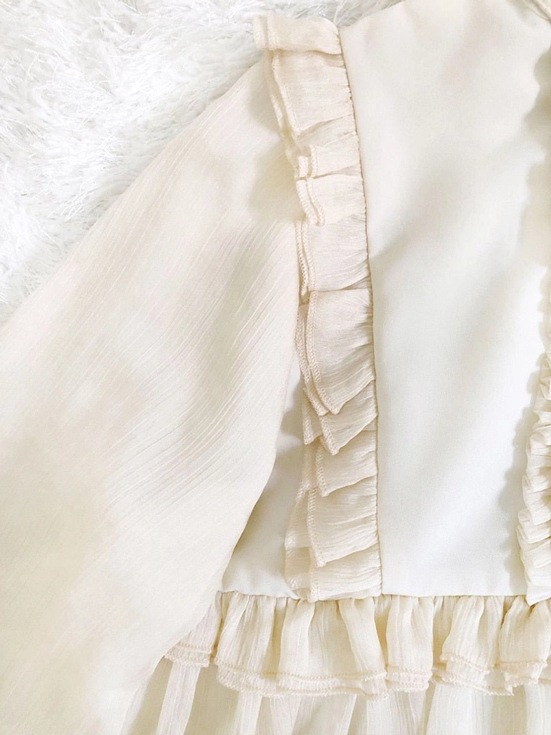 Close-up of cream white steampunk blouse ruffled trim detail showing layered chiffon texture and soft fabric construction