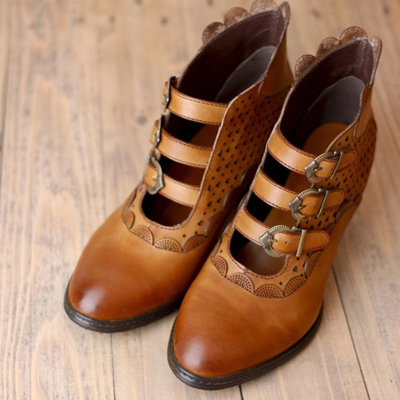 Steampunk leather ankle boots paired front view displaying cutout upper leather panels, triple buckle fastening system, and scalloped heel collar detail