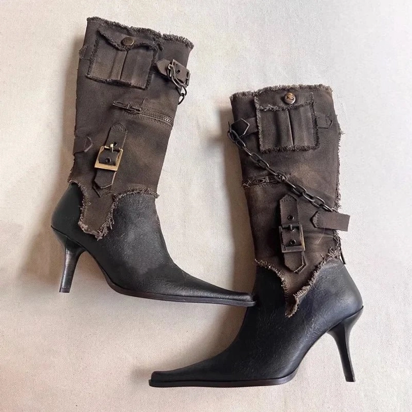 Steampunk high-heeled mid-calf boots side flat lay, distressed leather base with frayed canvas upper, decorative flap pockets and chain hardware
