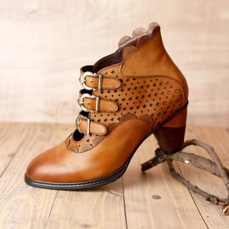 Steampunk leather ankle boot right side profile highlighting perforated side panels, stacked metal buckles, geometric cutout design, and block heel structure
