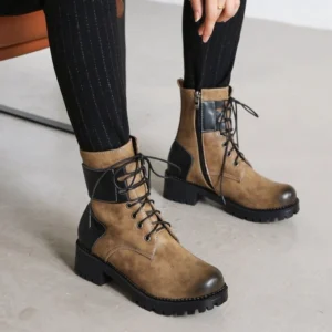 Steampunk combat boots side view worn on model with pinstriped pants - showing integrated side zipper closure, lace-up detail, block heel, and faux leather texture