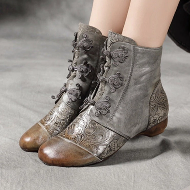Woman wearing steampunk flat ankle boots with embossed floral leather design, side view on gray background