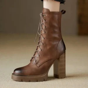 Brown leather distressed combat boots on model, side profile view showing chunky heel and lace-up closure with black ankle cuff