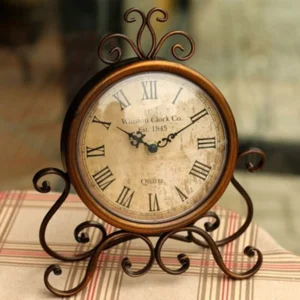 Steampunk bronze desk clock with wrought iron frame and Roman numeral dial, frontal view on plaid cloth backdrop