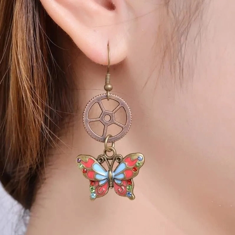 Steampunk butterfly gear earrings worn on female ear showing antique bronze hardware and enamel butterfly decoration in side profile