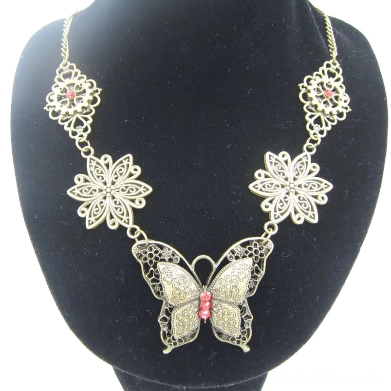 Steampunk butterfly necklace displayed on black jewelry bust, featuring vintage bronze finish with red gem accent and ornate silver filigree floral details on pendant