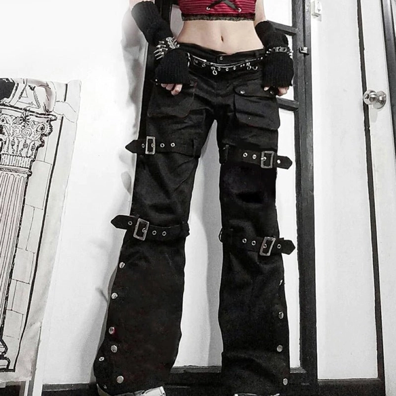 Front view of steampunk cargo pants on model indoors showing studded waist belt and silver buckle details with low-rise silhouette