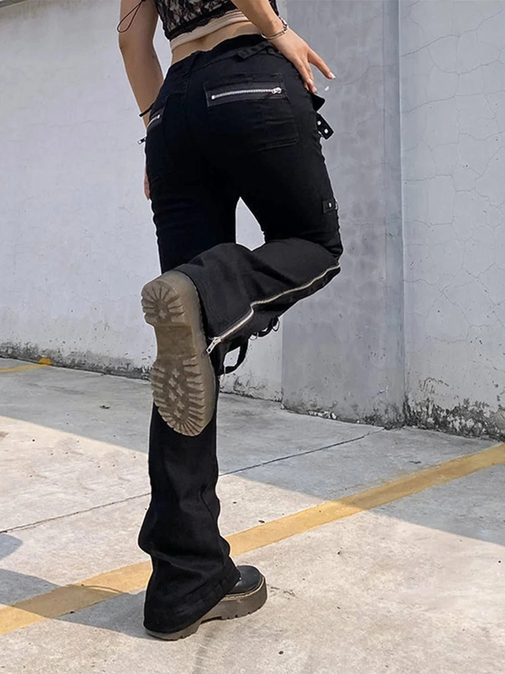 Back view of black steampunk flared pants featuring rear zipper pocket and dramatic flare cut paired with platform boots