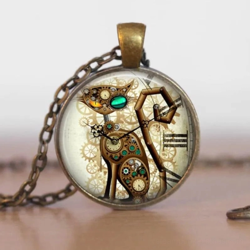 Steampunk mechanical cat pendant necklace with bronze metal frame, glass cabochon, intricate gear details, and glowing green gem eye on wooden desktop