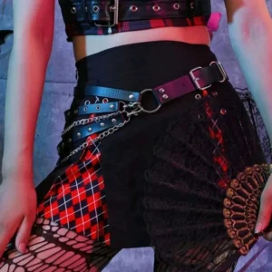 Gothic steampunk leather chain belt with layered dual straps and silver metal rivets, front-facing waist view paired with red plaid skirt, displaying linked chains and studded industrial details