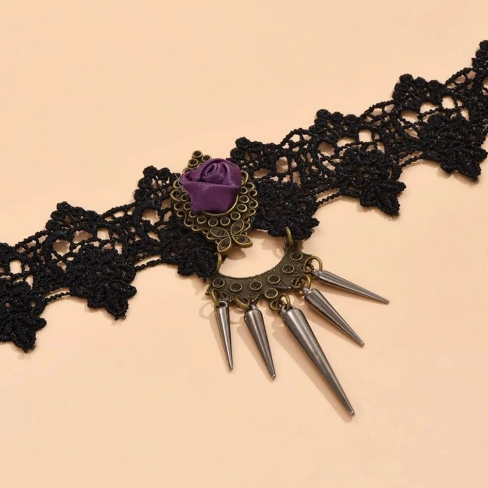 Close-up flat lay of gothic steampunk lace choker showing intricate black crochet lace detail, bronze metal hardware, and silver spike charms on beige background
