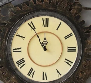 Close-up detail of steampunk wall clock showing aged metal gear border, ornate brass clock hands, and Roman numerals