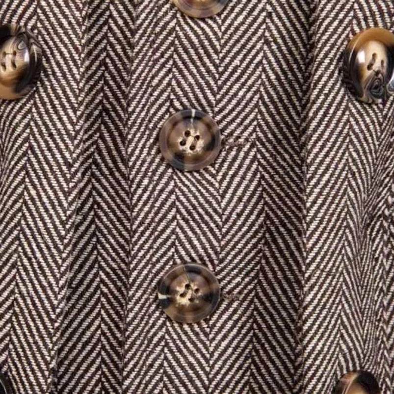Close-up macro detail of steampunk coat herringbone weave pattern and decorative brown buttons showing premium fabric construction and industrial aesthetic elements