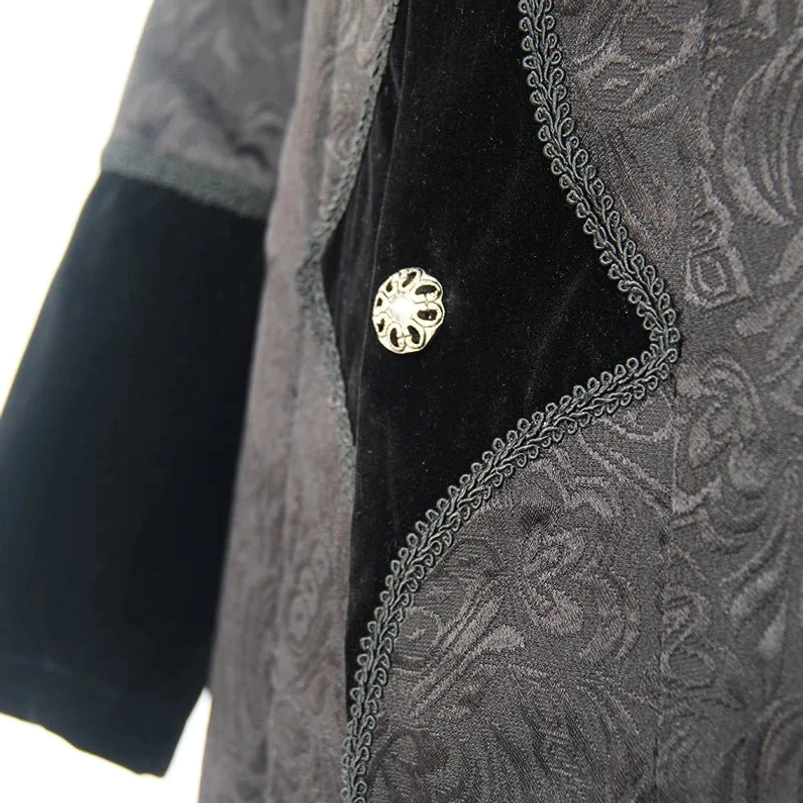 Close-up macro view of gothic steampunk coat fabric showing ornate metal buttons lace embroidery and mixed velvet jacquard texture