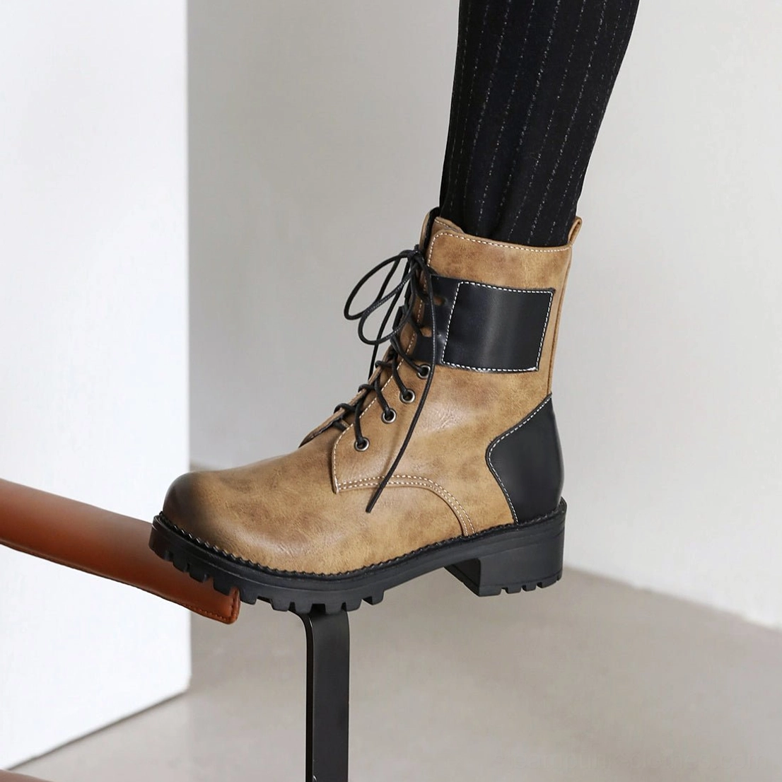 Close-up detail shot of single steampunk lace-up combat boot - aged brown vintage finish, black accent panels, faux leather texture, industrial block heel and lacing system