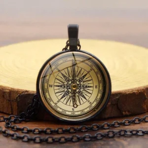 steampunk compass necklace with black metal frame and glass compass dial displayed on wooden surface, vintage navigation design
