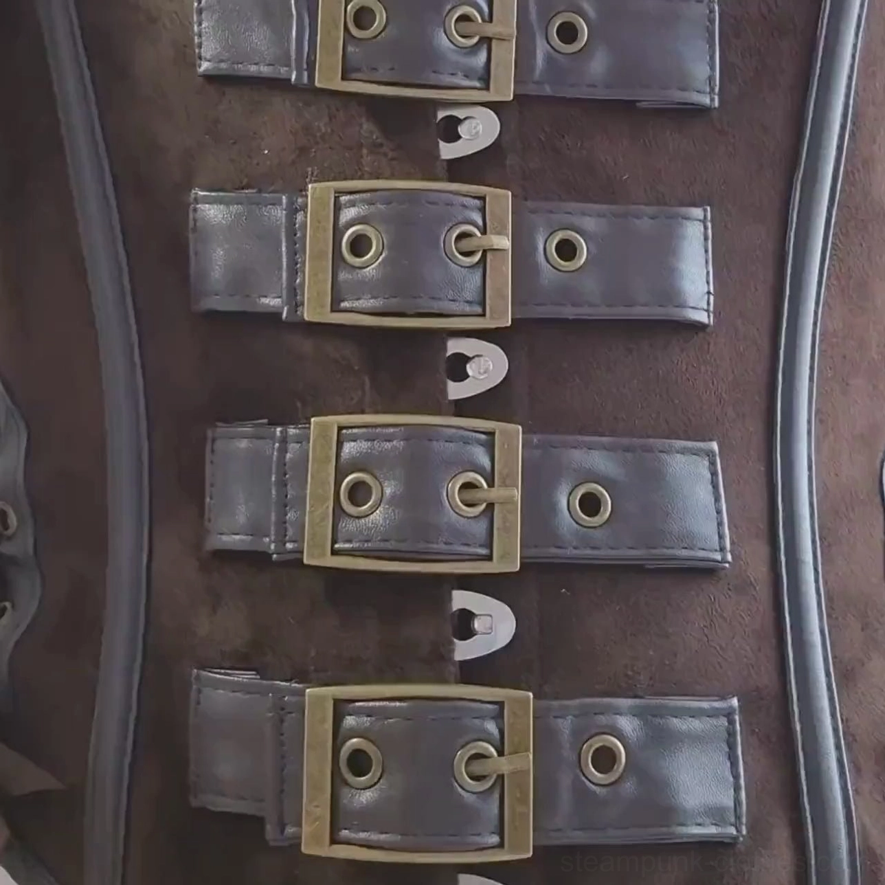 Close-up flat lay of antique brass buckles and dark brown suede corset hardware details