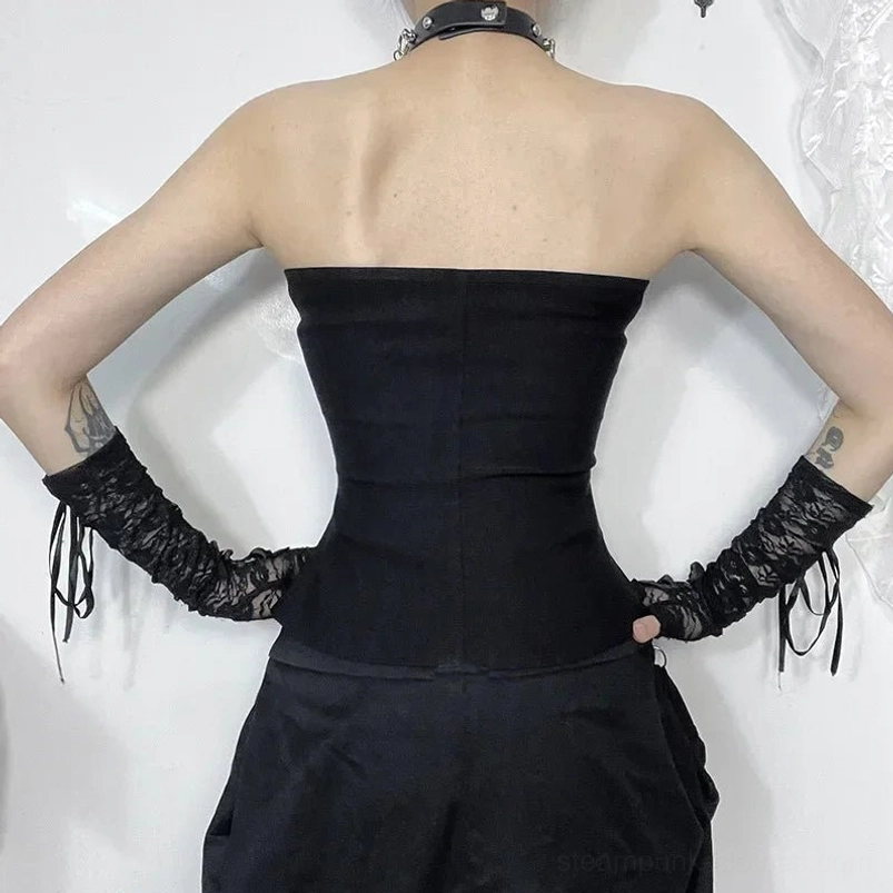 Back view of black strapless steampunk corset showing solid back design with tasseled lace gloves on tattooed model against white lace studio backdrop
