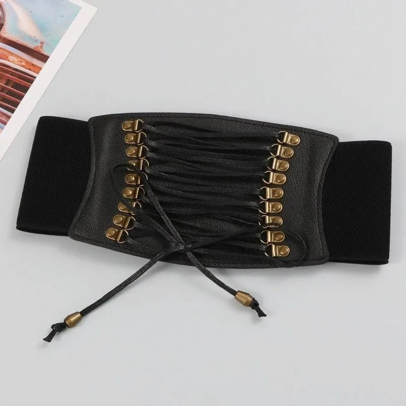 Flat-lay overhead view of wide black steampunk corset waist belt displaying complete lace-up design, elastic side panels, antique bronze hardware distribution, and structural engineering